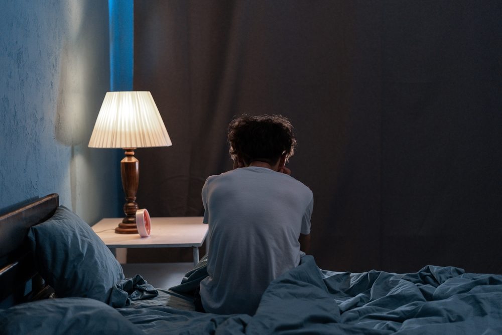 Mand sidder med ryg til i sengen og ligner en, der ikke kan sove