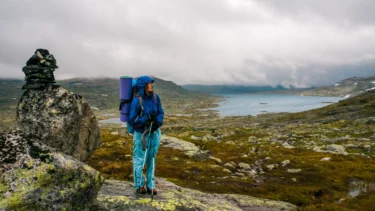 En kvinde står på en sten i et norsk fjeldlandskab