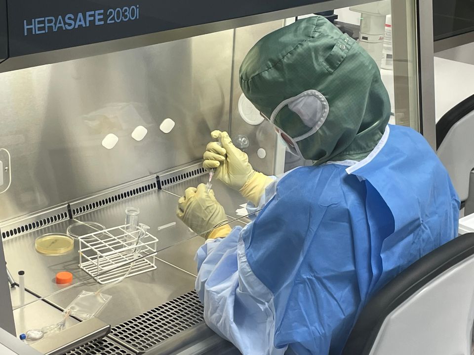 En forsker iført værnemidler sidder i laboratoriet med en pipette.