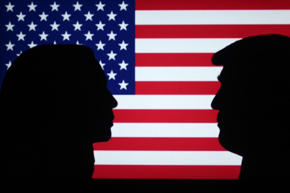 Silhuetter af Kamala Harris og Donald Trump foran et amerikansk flag.