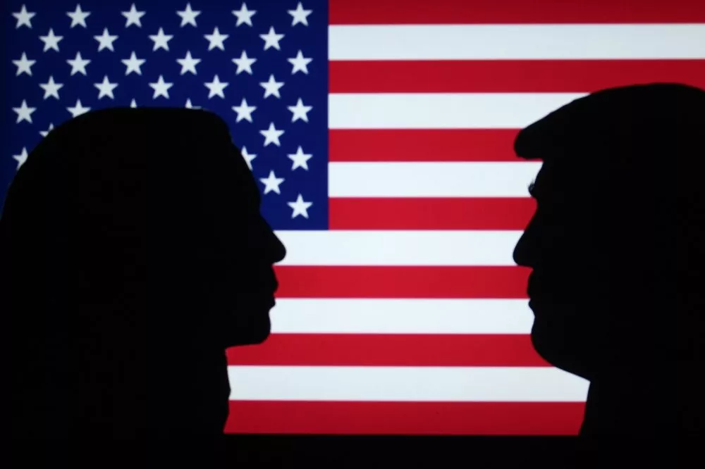 Silhuetter af Kamala Harris og Donald Trump foran et amerikansk flag.