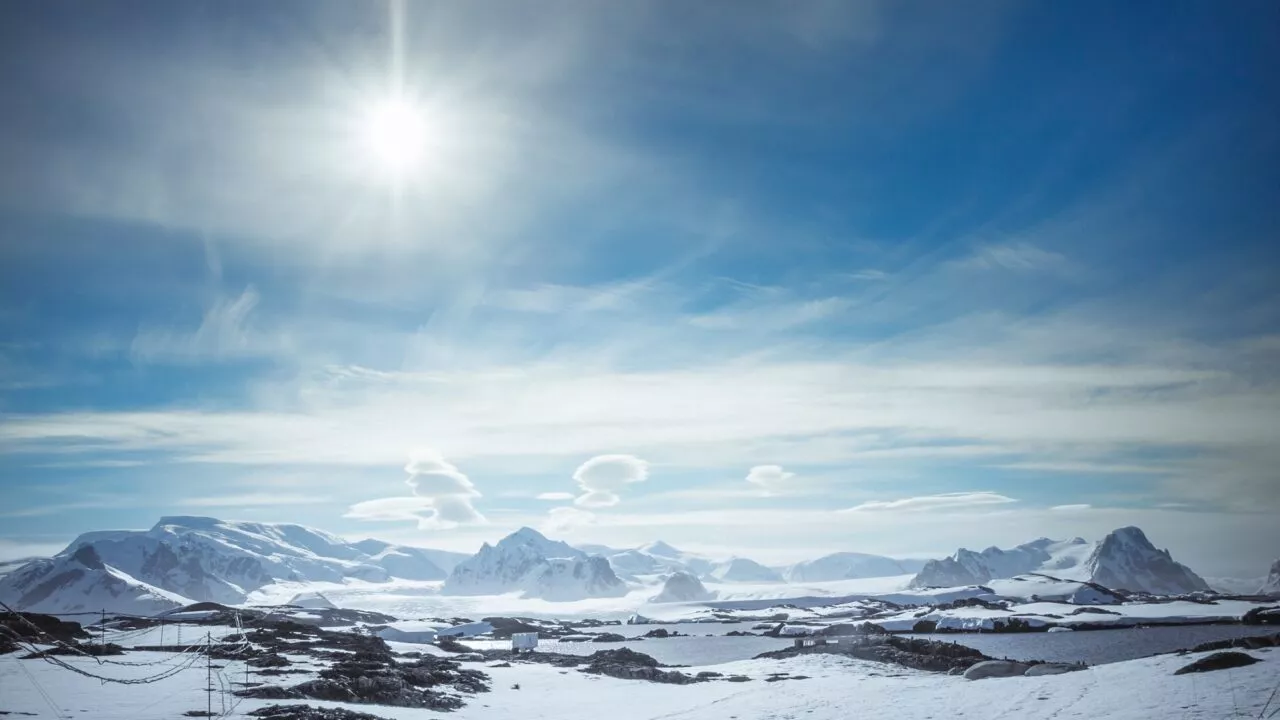 Arktisk landskab med bjerge, sne og sol
