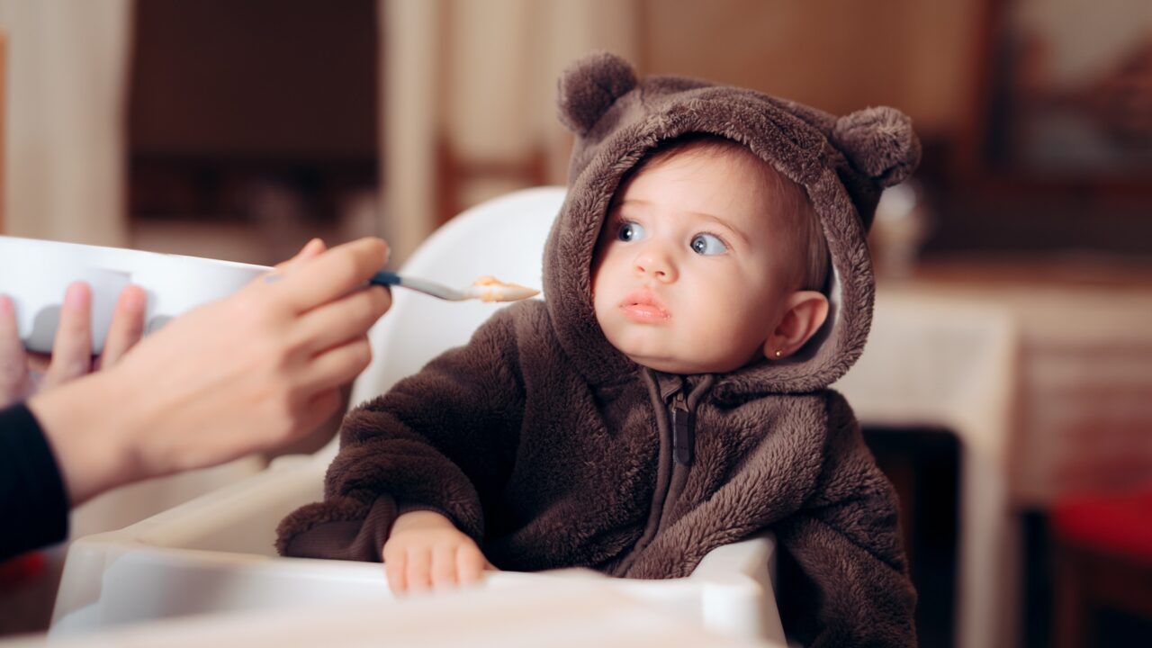 en baby ser skeptisk ud, da den bliver tilbudt noget mad på en ske