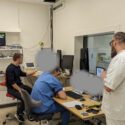 Et computerrum fyldt med forskere og hospitalspersonale. De kigger allesammen i retning af computeren, hvor man kan se fMRI-scanningen