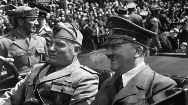 Adolf Hitler og Benito Mussolini sidder i en åben bil og kører gennem München. Der står tusindvis af folk og ser på.