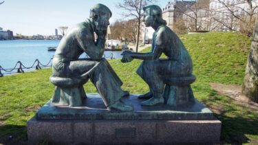 Stenskulpturer af to unge mennesker, der sidder overfor hinanden af Johannes Hansen.
