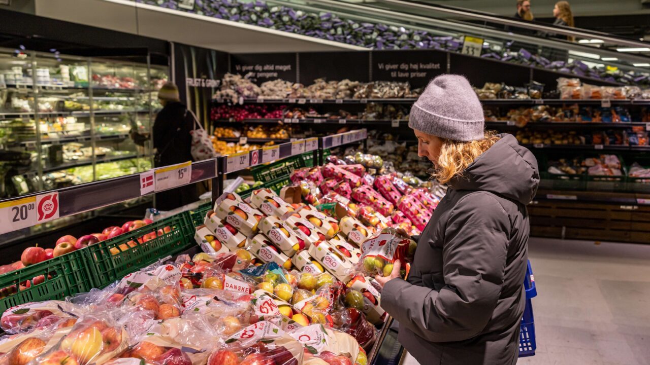 en kvinde i et dansk supermarked kigger på et æble