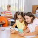 to piger giver på hver deres telefon i et klasseværelse