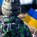 Ryggen af et ukrainsk barn der holder et flag