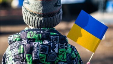 Ryggen af et ukrainsk barn der holder et flag