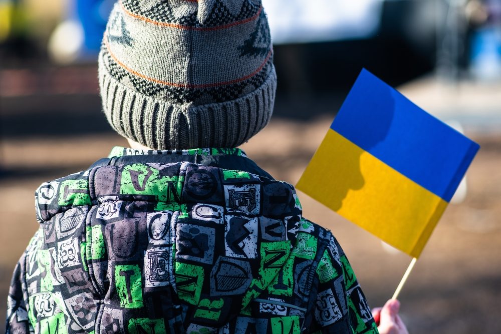 Ryggen af et ukrainsk barn der holder et flag