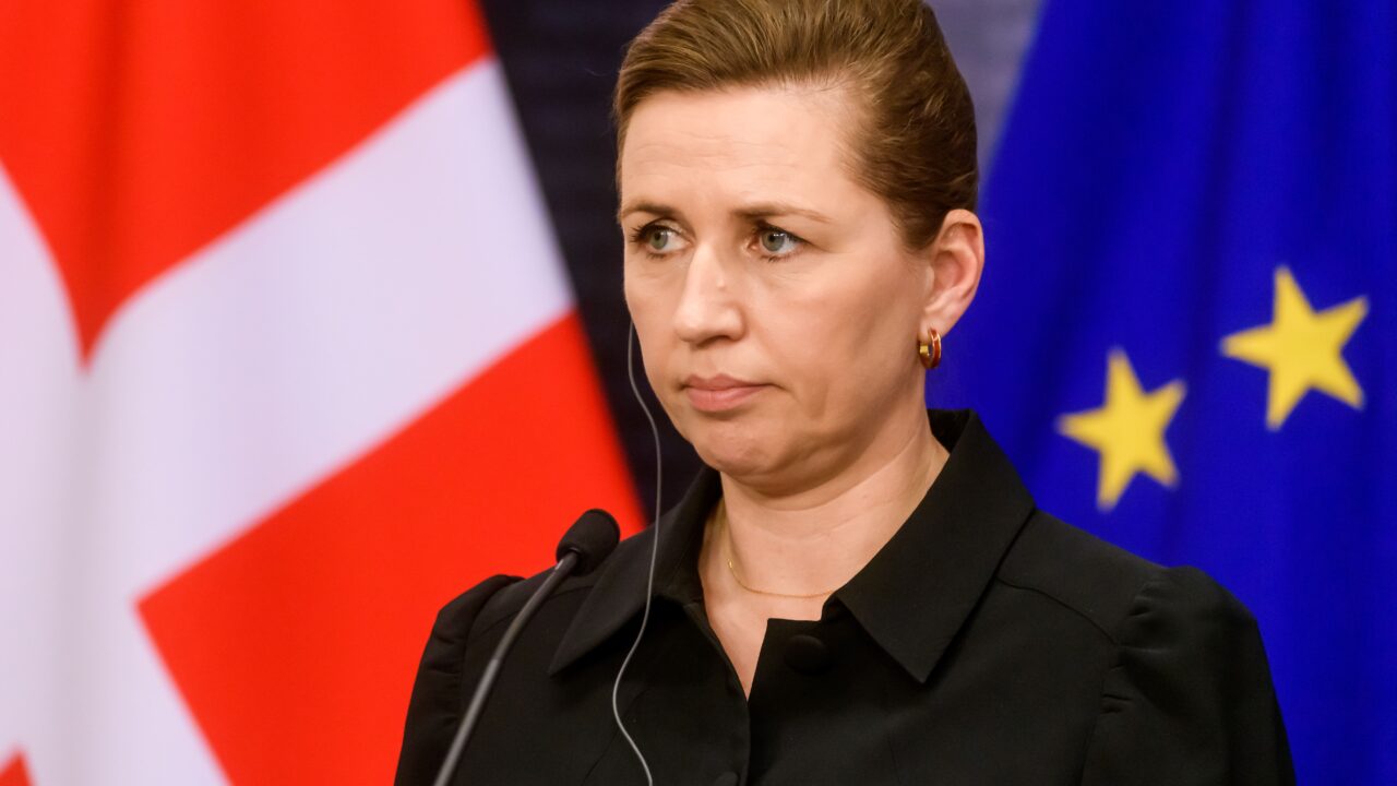 Mette Frederiksen ser alvorlig ud med EU- og Danmarksflag i baggrunden