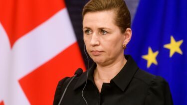 Mette Frederiksen ser alvorlig ud med EU- og Danmarksflag i baggrunden