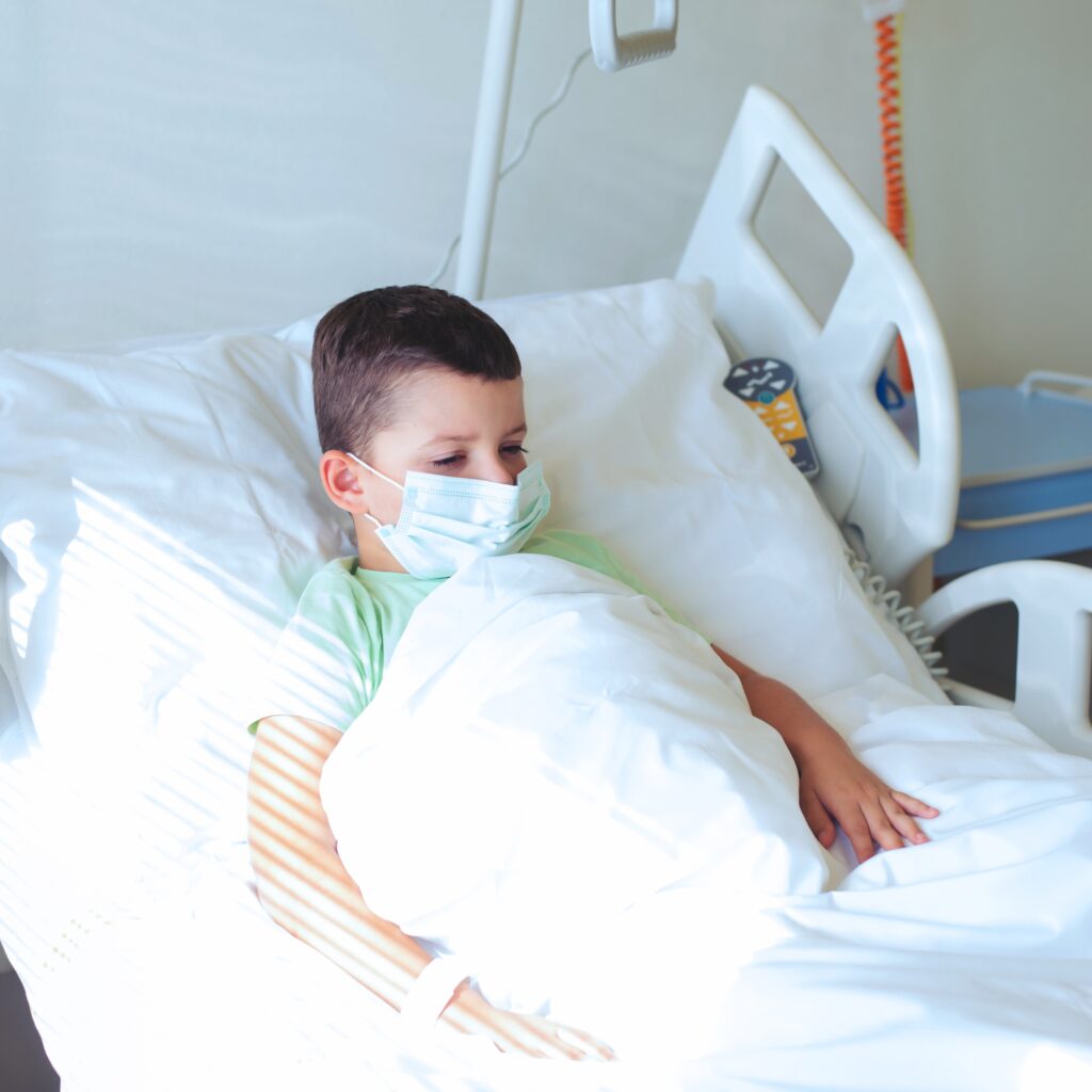 Et barn ligger i en hospitalsseng
