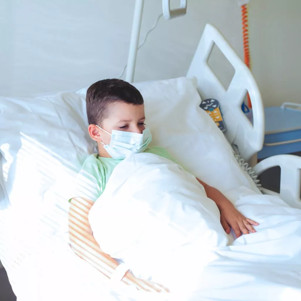 Et barn ligger i en hospitalsseng