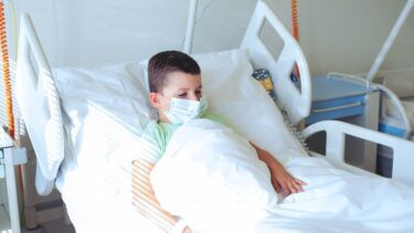 Et barn ligger i en hospitalsseng