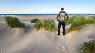 En mand står i klitterne og kigger ud over havet