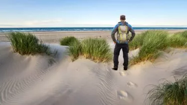 En mand står i klitterne og kigger ud over havet