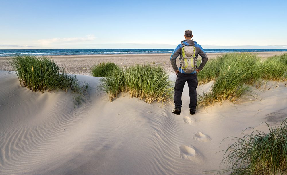 En mand står i klitterne og kigger ud over havet