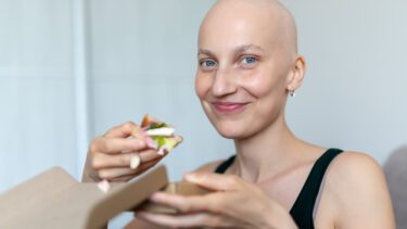 Skaldet kvinde med en rugbrødsmad i hånden