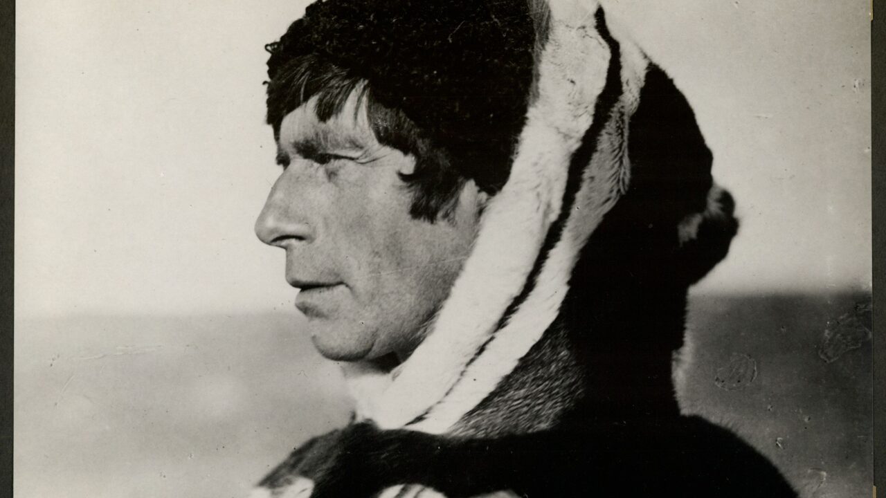 Sorthvid-fotografi af Knud Rasmussen iført sælskinsjakke med hætte