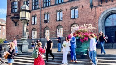 Et nygift par står foran Københavns Rådhus.