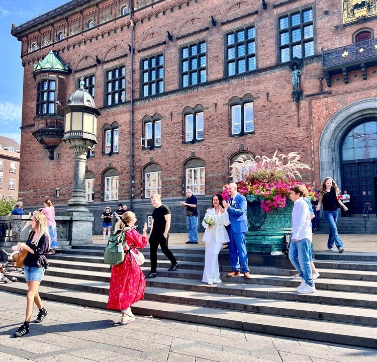 Et nygift par står foran Københavns Rådhus.