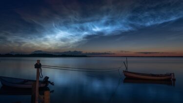 En sommernatthimmel over vandet i Danmark, på himlen ses lysende natskyer, glødende natskyer