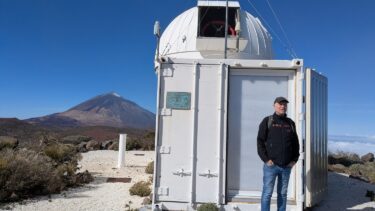 Den sneklædte top af vulkanen Teide ses bag det danske teleskop. Containeren rummer computere, der styrer teleskopet, samt den spektrograf, der røber stjernernes svingninger. (Foto: Henrik Bendix)