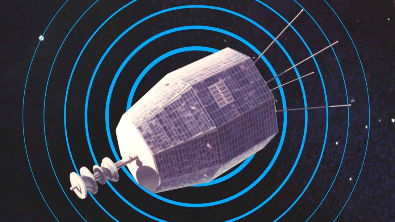 En satellit med en sekskantet krop dækket af solpaneler og antenner, der strækker sig fra den ene ende, svæver i det ydre rums mørke vidder med en baggrund af blå radiobølger.