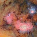 Et levende billede af kosmos, der viser stjernetåger med lyserøde, blå og orange skyer af gas og støv, spredte stjerner og indviklede kosmiske strukturer mod en baggrund i det ydre rum.