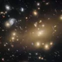 Et dybderumsbillede, der viser mange lyse galakser, spiralgalakser og fjerne stjernehobe spredt ud over en mørk baggrund, optaget af Hubble-teleskopet.