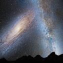 En fantastisk nattehimmel viser Mælkevejen og Andromeda-galaksen over en silhuet af forrevne bjergtoppe, fyldt med utallige stjerner og kosmiske skyer.