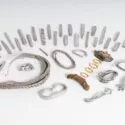 En samling af sølvbarrer, armbånd, ringe og andre smykker fra vikingetiden udstillet på en hvid overflade, hvor nogle af genstandene har indviklede mønstre, og der er en rusten metalgenstand blandt dem.