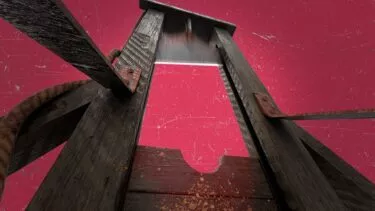 Lavvinkelbillede af en forvitret guillotine af træ på en rød baggrund med en rusten klinge og et reb, der antyder en ildevarslende og historisk atmosfære.