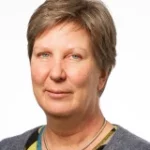 Nina Skaarup kigger ind i kameraet med et neutralt udtryk mod en hvid baggrund.