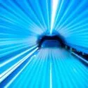 Et nærbillede og en vidvinkel inde i et solarium, der viser lyseblå UV-lys i det buede indre, som stråler ind mod midten og skaber en glødende, futuristisk effekt.