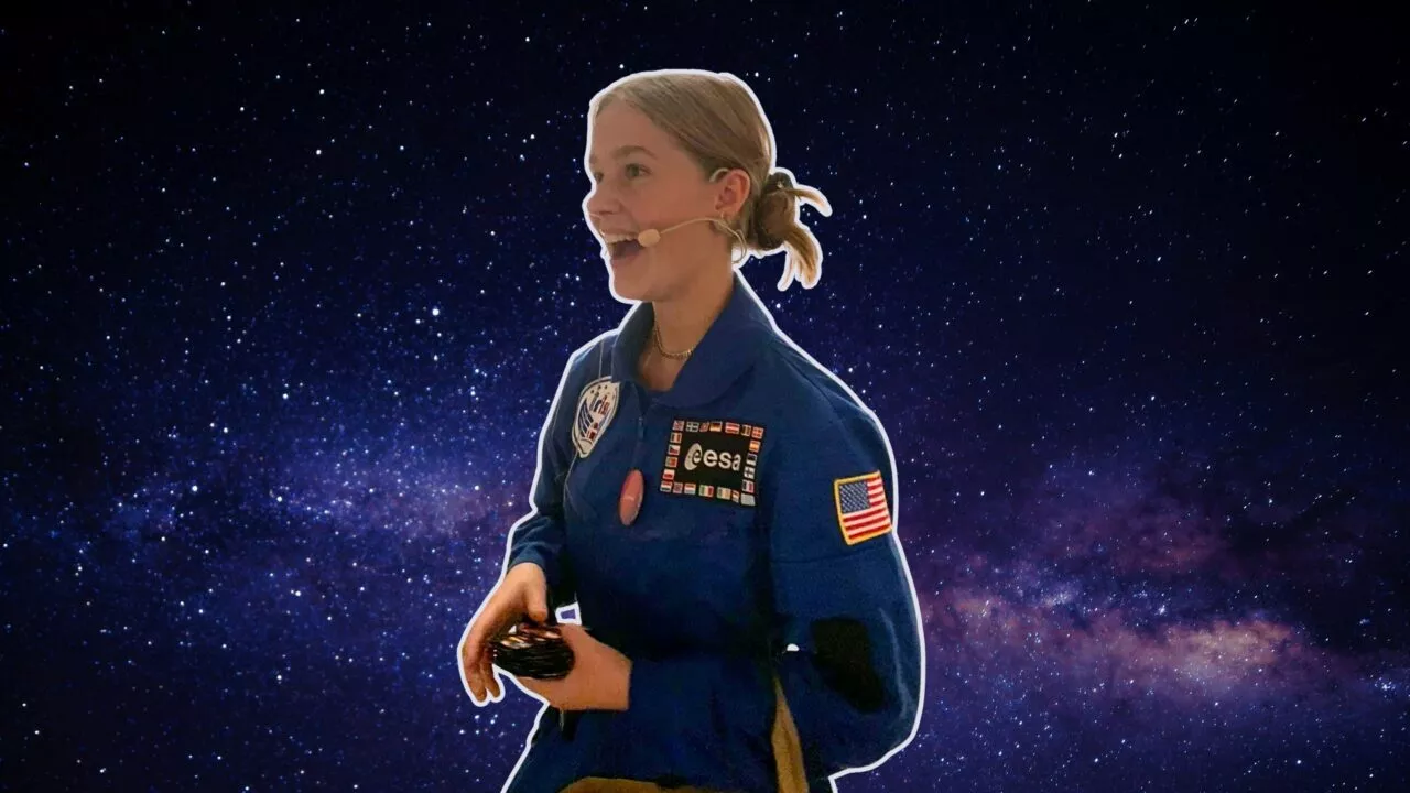 En ung person i blå astronautdragt og headset står på en stjerneklar nattehimmel og bærer patches fra ESA og USA's flag.
