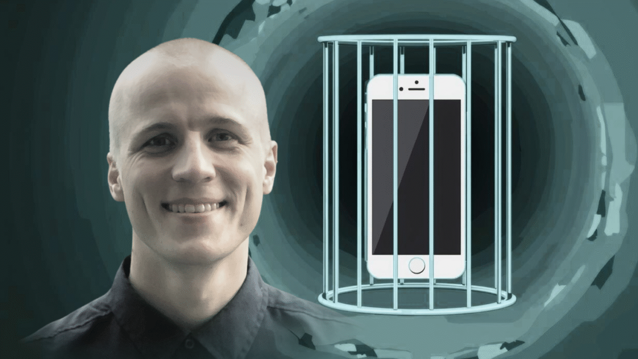 En smilende person med glatbarberet hoved står ved siden af en illustration af en smartphone, der er låst inde i et metalbur, på en mørk, abstrakt baggrund.