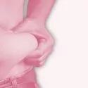 En person iført jeans klemmer på huden og fedtet på sin bare mave med den ene hånd. Billedet har et lyserødt filter.