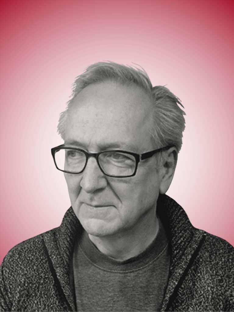 Et gråtonet foto af en ældre mand med briller og gråt hår, iført en sweater med lynlås over en t-shirt. Han har et eftertænksomt udtryk og kigger til siden. Baggrunden er en pink gradient.