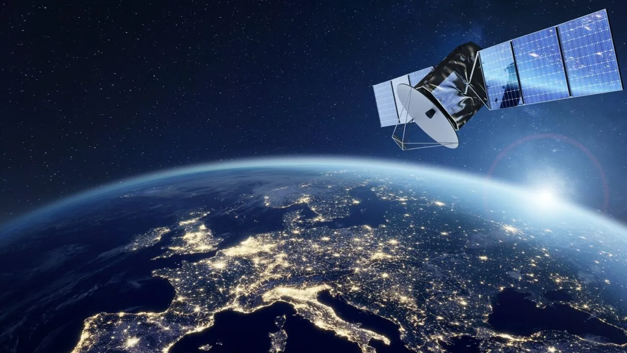 En satellit kredser over Europa om natten, hvor man kan se byernes lys over hele kontinentet, og solen står op over jordens krumning på en stjernefyldt himmel.