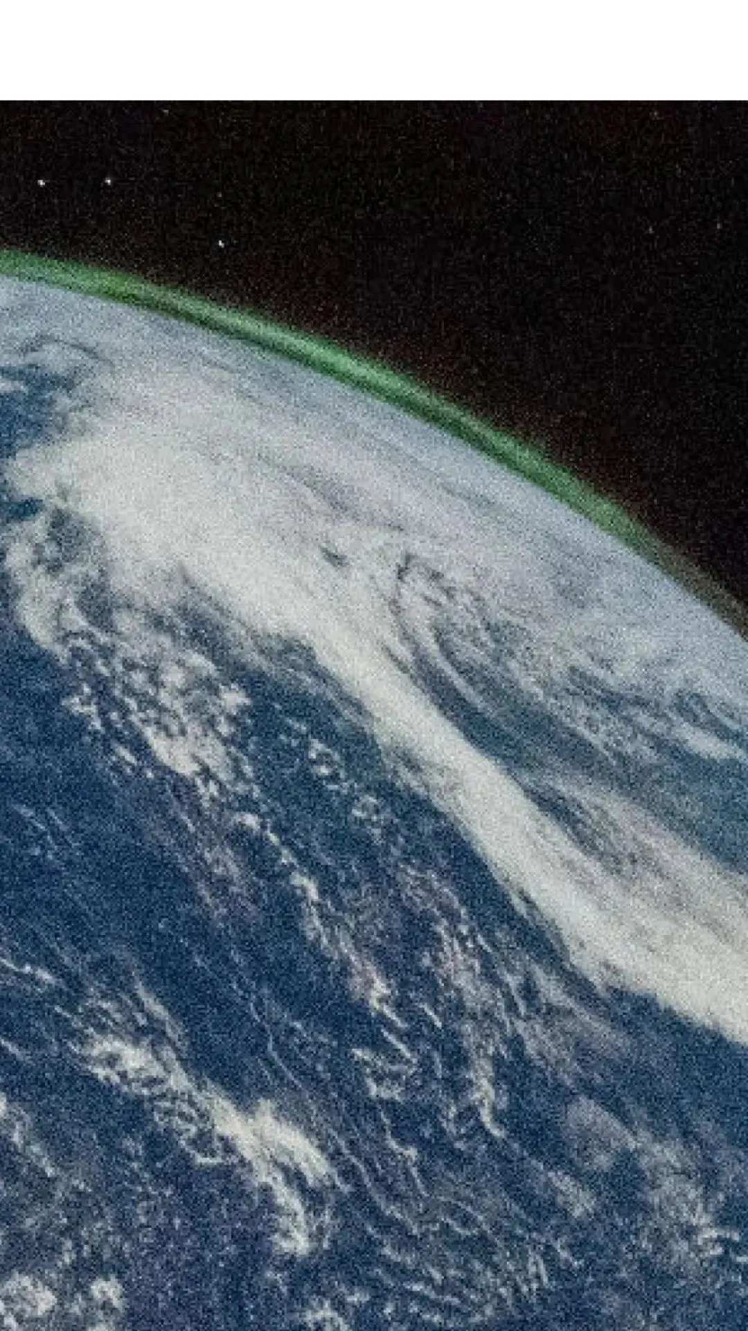 Et billede af Jorden fra rummet viser hvirvlende hvide skyer over blå oceaner. Et svagt grønt nordlys er synligt langs den buede kant af planeten, med det ydre rums mørke i baggrunden.