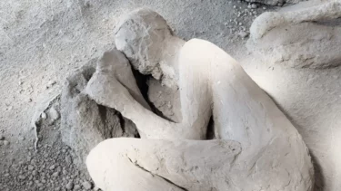 En gipsafstøbning af en person i sammenkrøbet fosterstilling, bevaret i aske og vulkanske rester, sandsynligvis fra Pompejis ruiner, der viser det øjeblik, hvor de blev overvældet af vulkanudbruddet.
