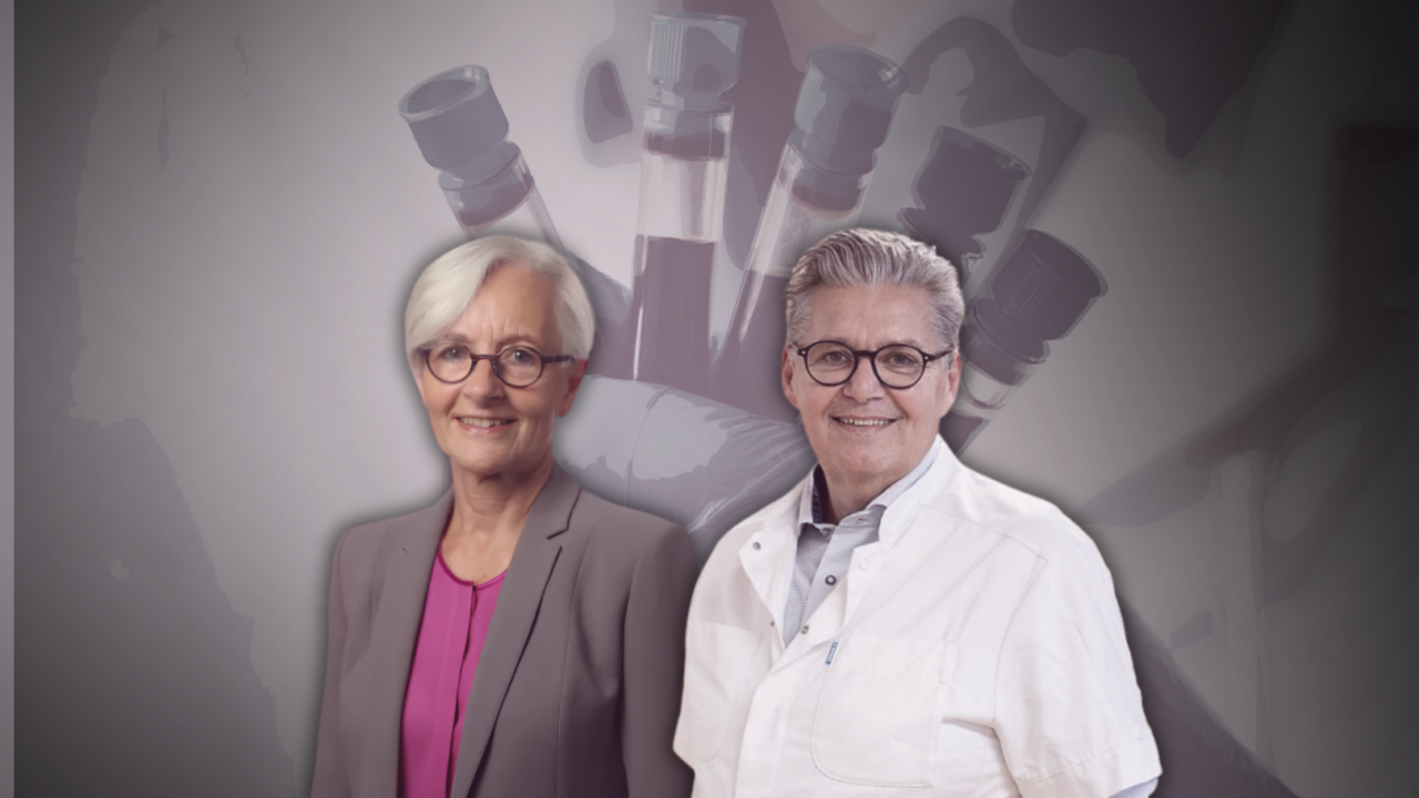 To ældre voksne med kort gråt hår står side om side; den ene bærer jakkesæt og briller, den anden en hvid laboratoriekittel. I baggrunden holder en handskeklædt hånd flere hætteglas, hvilket tyder på et medicinsk eller videnskabeligt miljø.