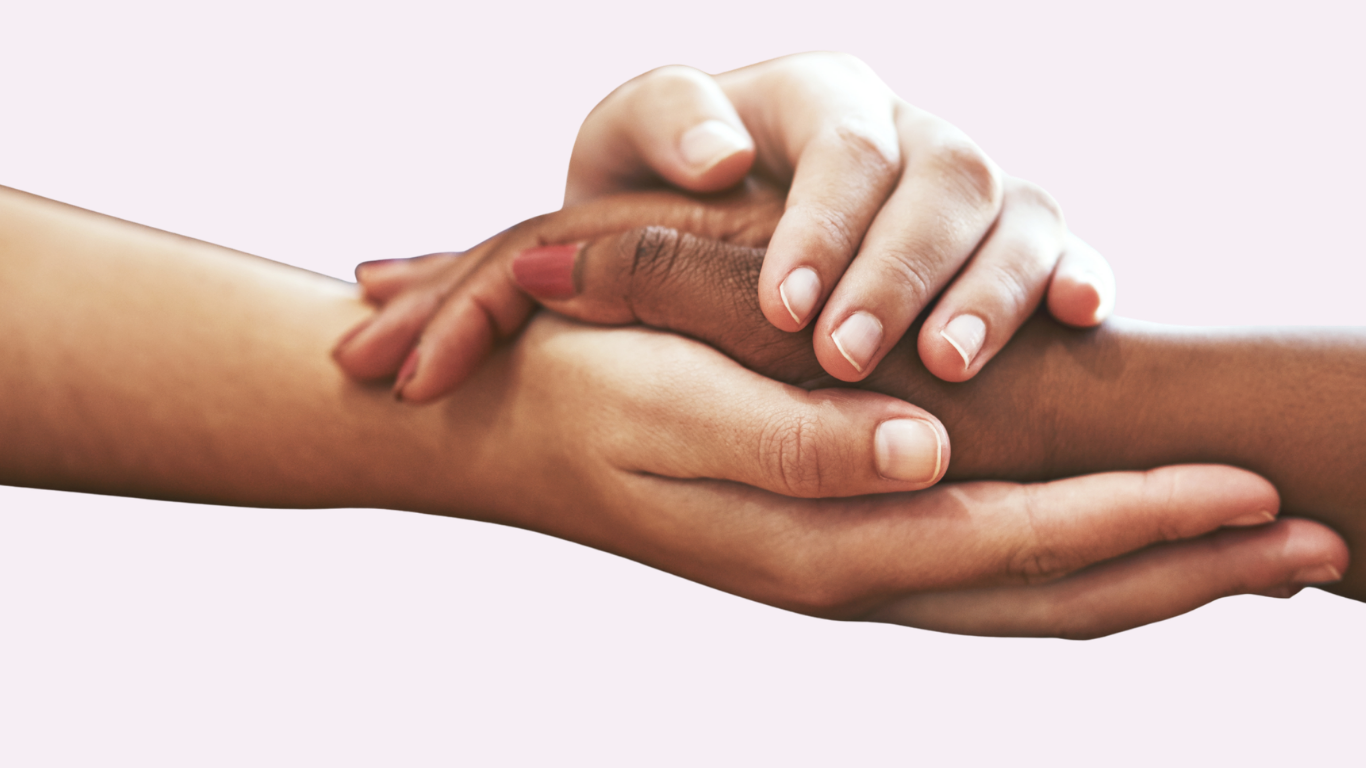 To hænder, der forsigtigt holder og trøster en anden persons hånd, symboliserer støtte, omsorg og medfølelse på en lyserød baggrund.