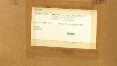 Et nærbillede af en brun kuvert med en maskinskrevet etiket. Etiketten indeholder ord som Serial, Subject: Flying Discs og Security - UNCLASSIFIED. Noget af teksten er falmet eller skjult.