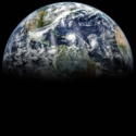 Et billede af Jorden set fra rummet, der viser Nord- og Mellemamerika, dele af Sydamerika og Atlanterhavet, med hvirvlende hvide skyer og synlige landmasser nedenunder. Den nederste halvdel af kloden forsvinder i mørket.