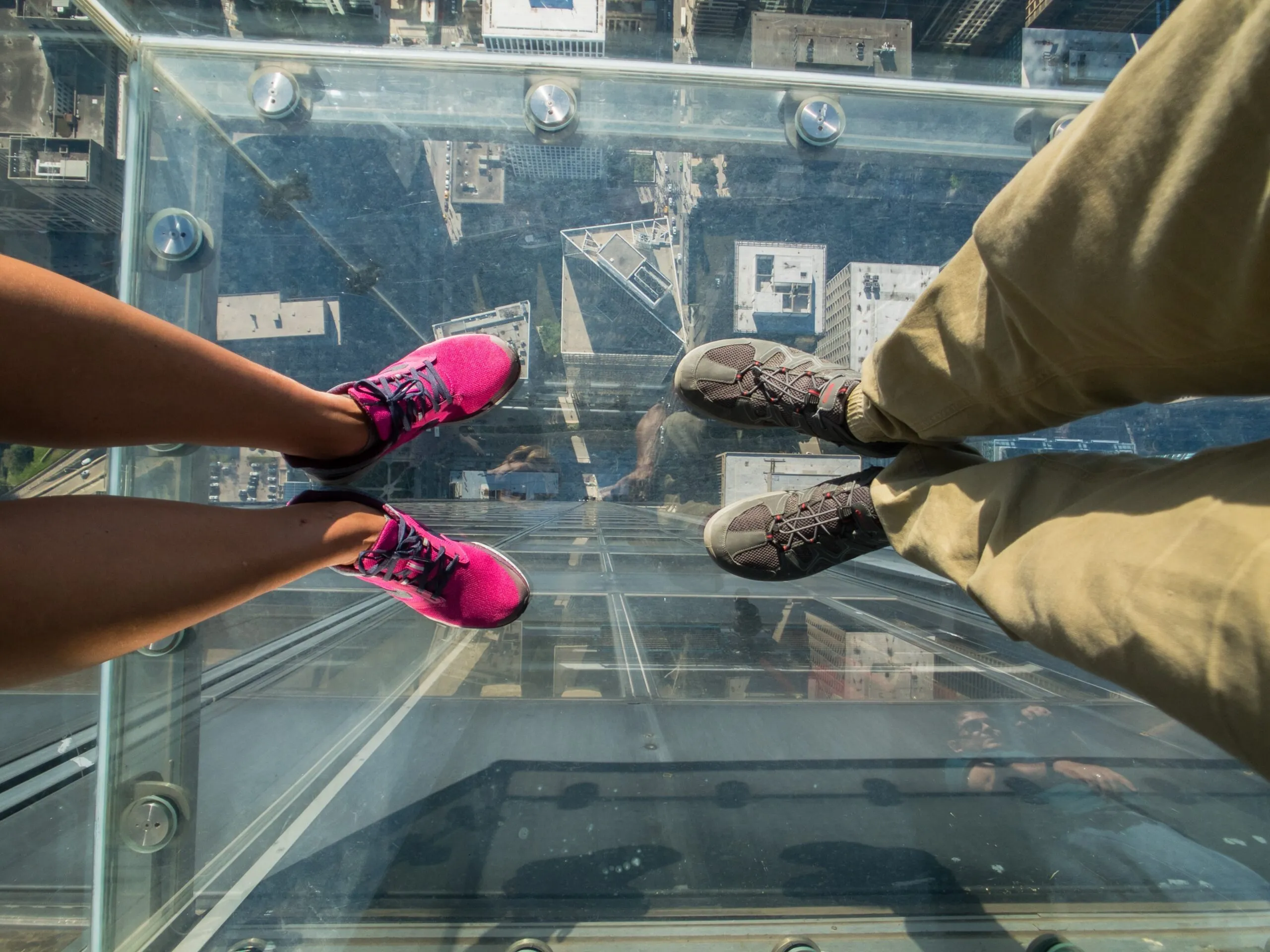 Turister poserer på et glasgulv i en skyskraber.