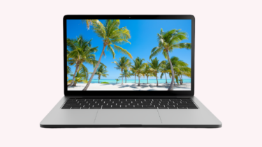 Laptop med screensaver af en hvid sandstrand med palmer
